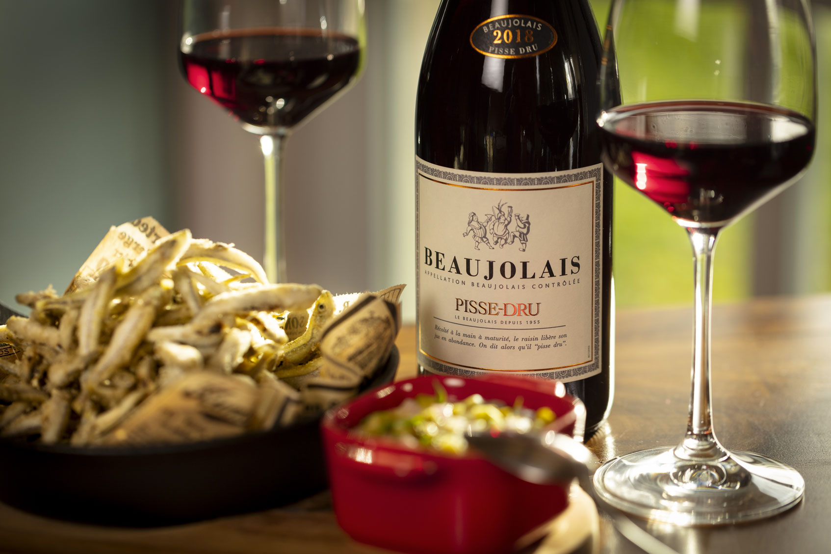 Bouteille de Beaujolais Pisse-Dru servie avec des éperlans frits