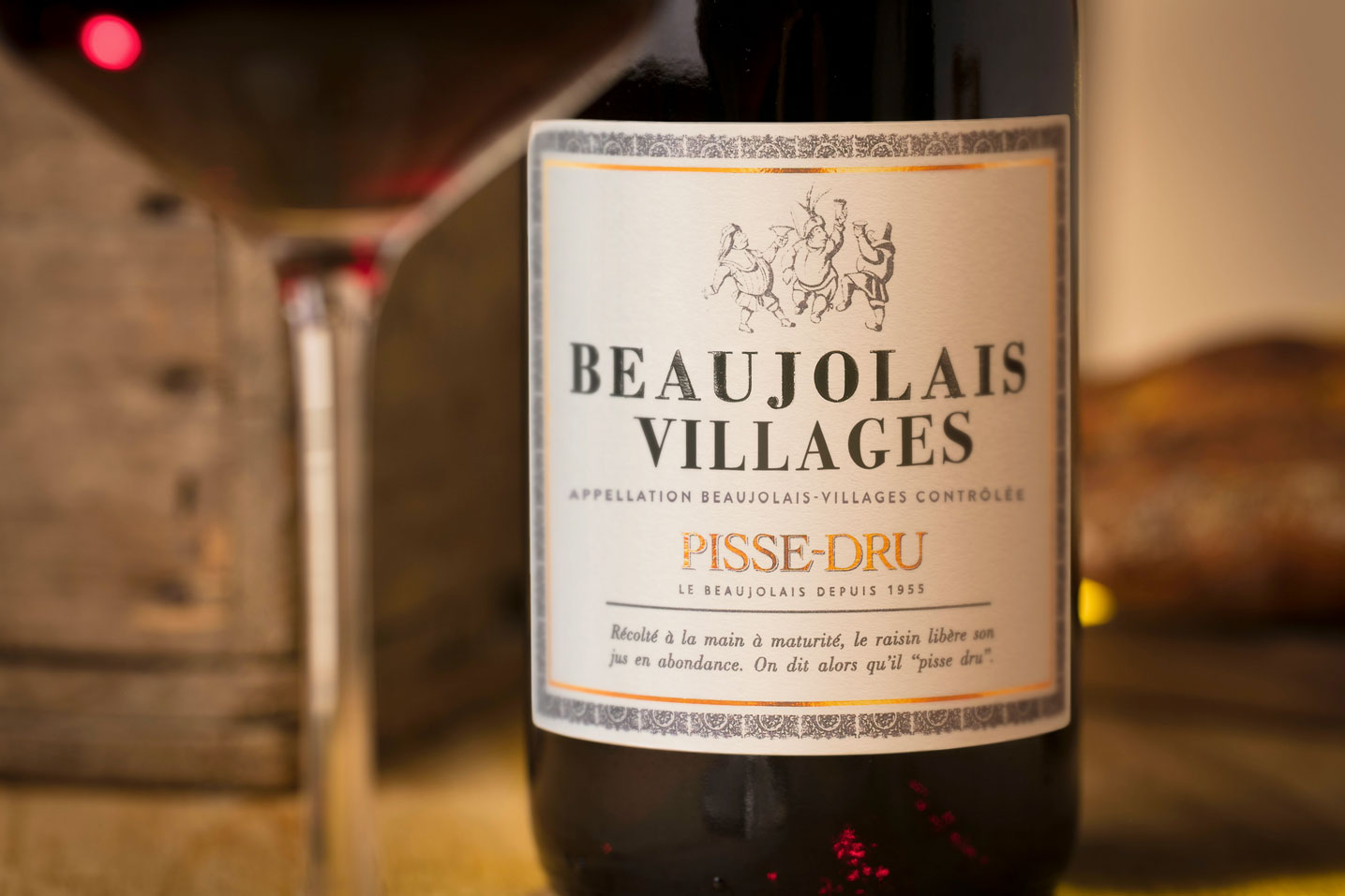 Bouteille de Beaujolais Village Pisse-Dru millésime 2019 en plan sérré avec un verre de vin